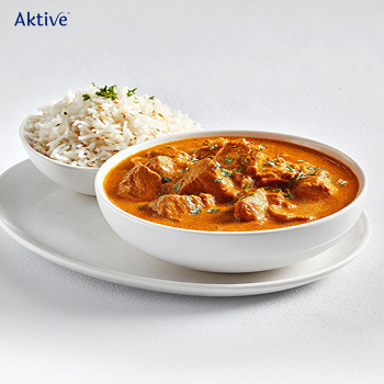 Butter chicken with jeera rice on a white plate