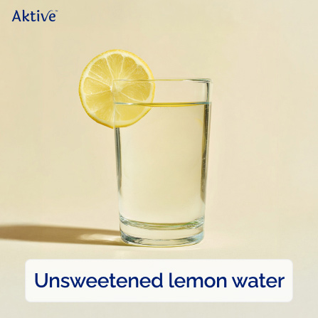 A glass of unsweetened lemon water with a lemon slice placed on the rim