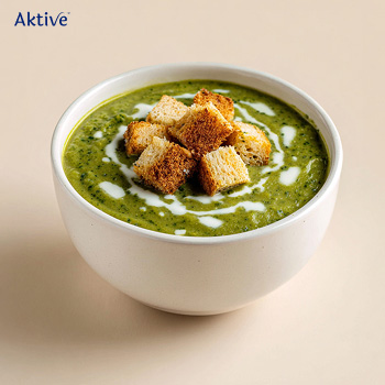 Bowl of spinach soup garnished with croutons